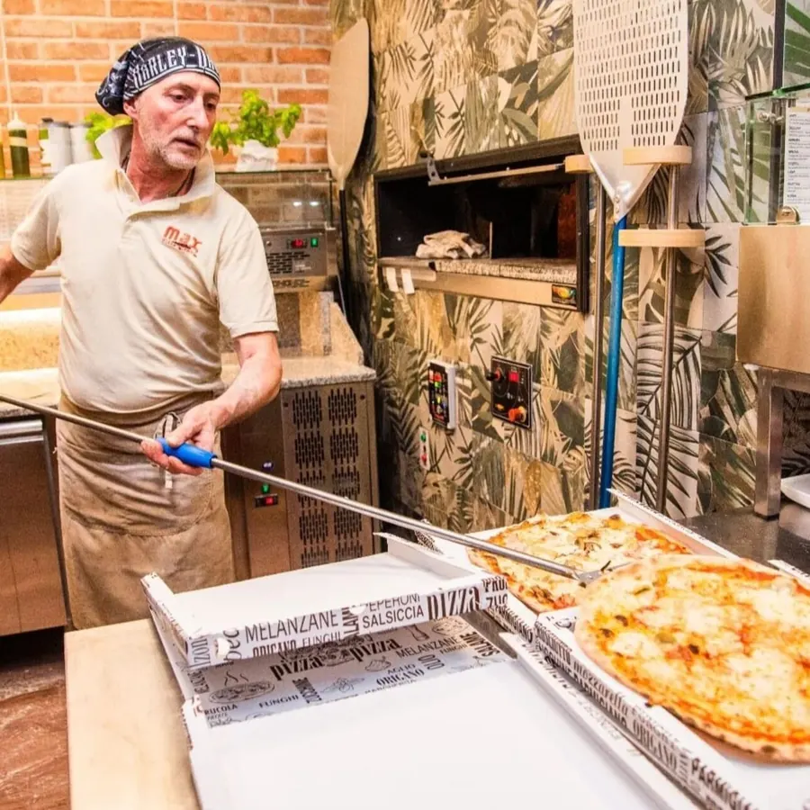 Il pizzaiolo con la pala mette nei cartoni le pizze appena sfornate