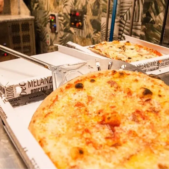 Pizza appena sfornata nel cartone, accanto alla pala